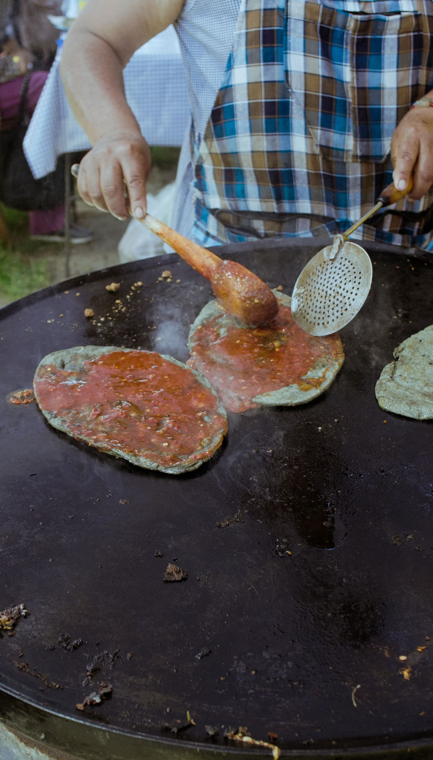 A chef skillfully prepares tortillas on a hot griddle, highlighting authentic Mexican cuisine.