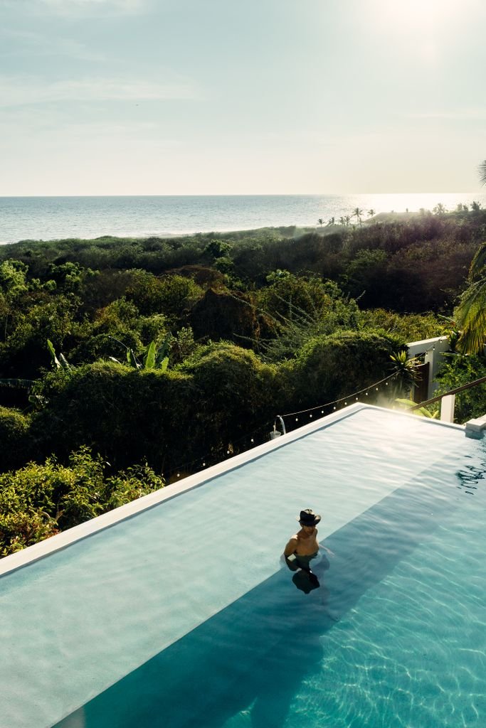 A person enjoys an infinity pool with stunning views of the Pacific Ocean in Puerto Escondido, Mexico.