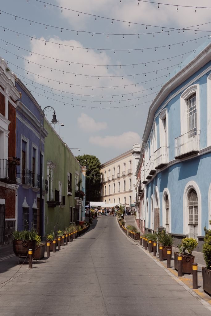 Charming colonial street in Puebla, Mexico, featuring colorful buildings and potted plants.