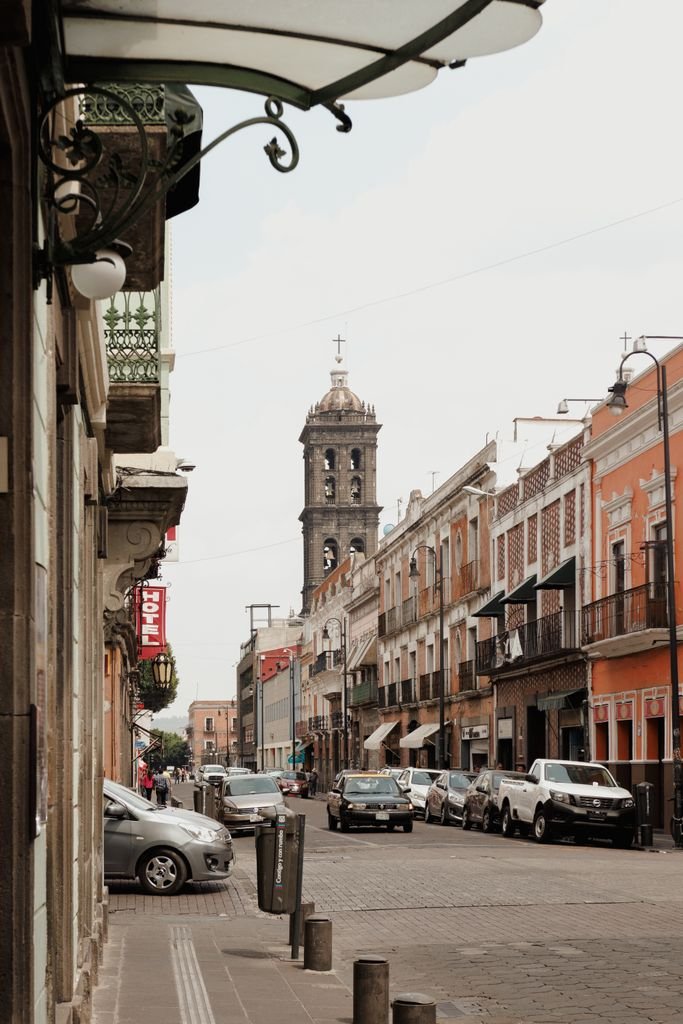 Charming street in Puebla, Mexico with colonial architecture and a prominent church tower.