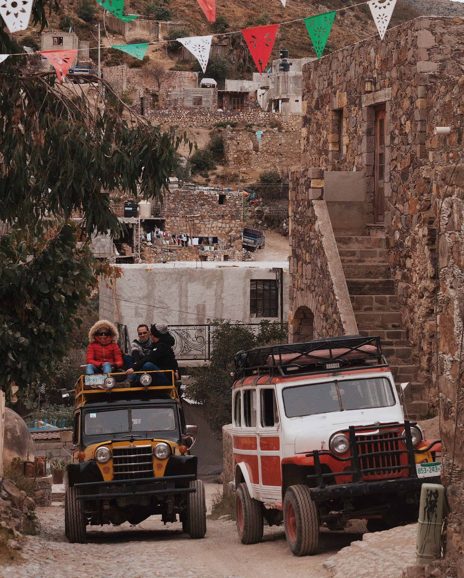 Colorful vintage vehicles navigate cobblestone streets in historic Real de Catorce, Mexico.