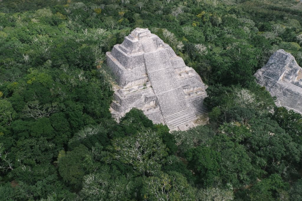 Discover the breathtaking aerial view of a Mayan pyramid amidst lush greenery in Campeche, Mexico.