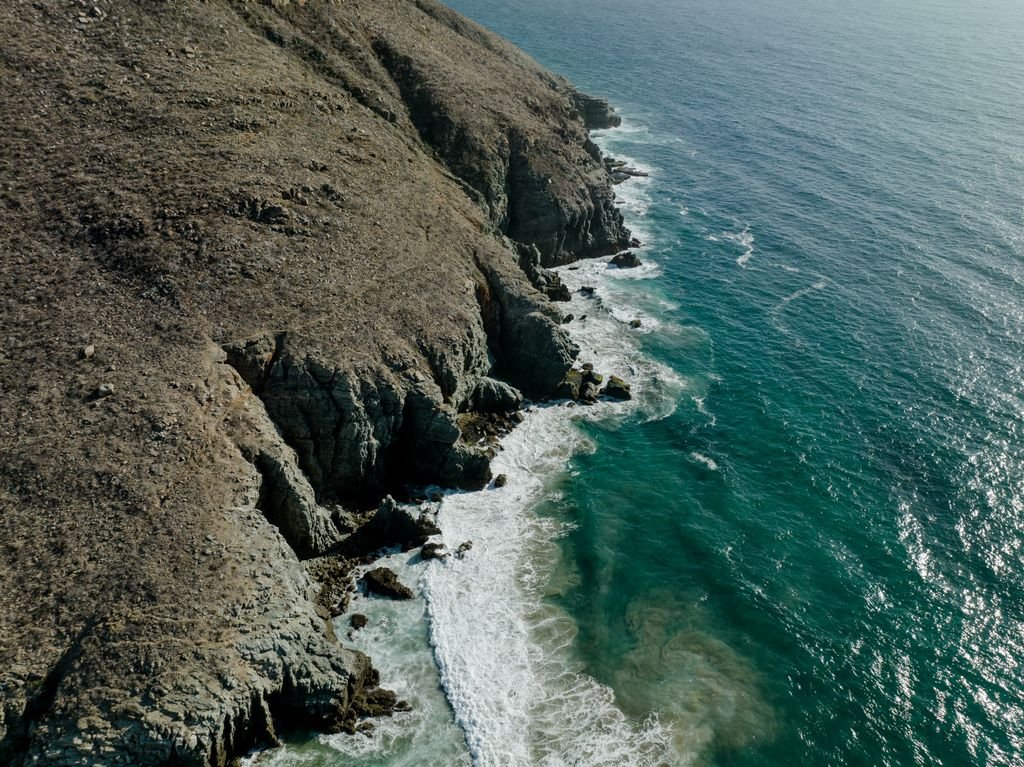 Drone shot of rugged cliffs meeting the ocean at Todos Santos, Baja California, Mexico.