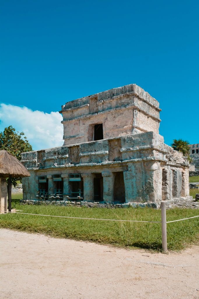 Explore the ancient architecture of Tulum's Temple of the Frescoes in Mexico, bathed in sunlight.
