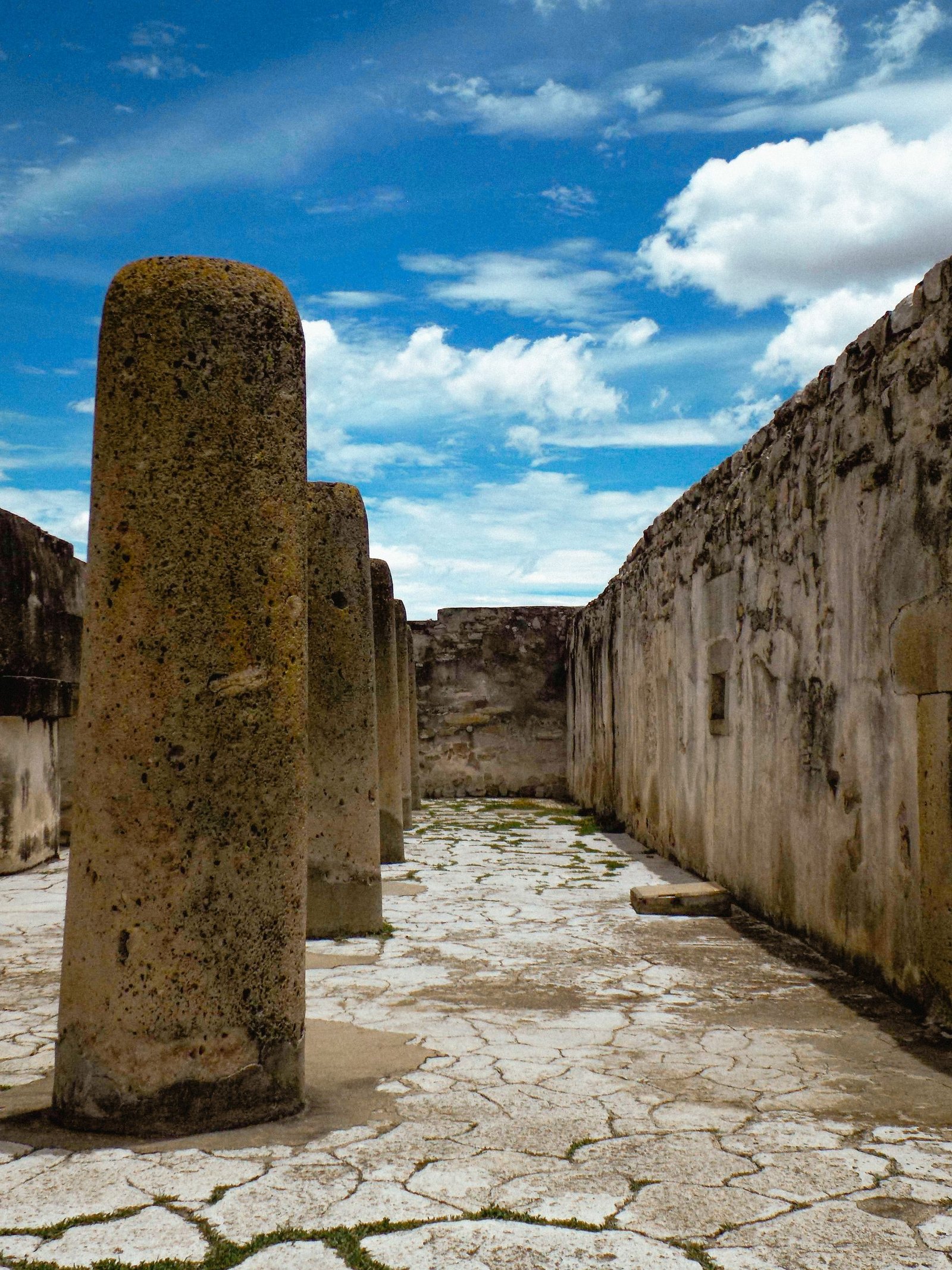 Explore the ancient ruins of Mitla in Oaxaca, featuring historic columns under a vibrant sky.