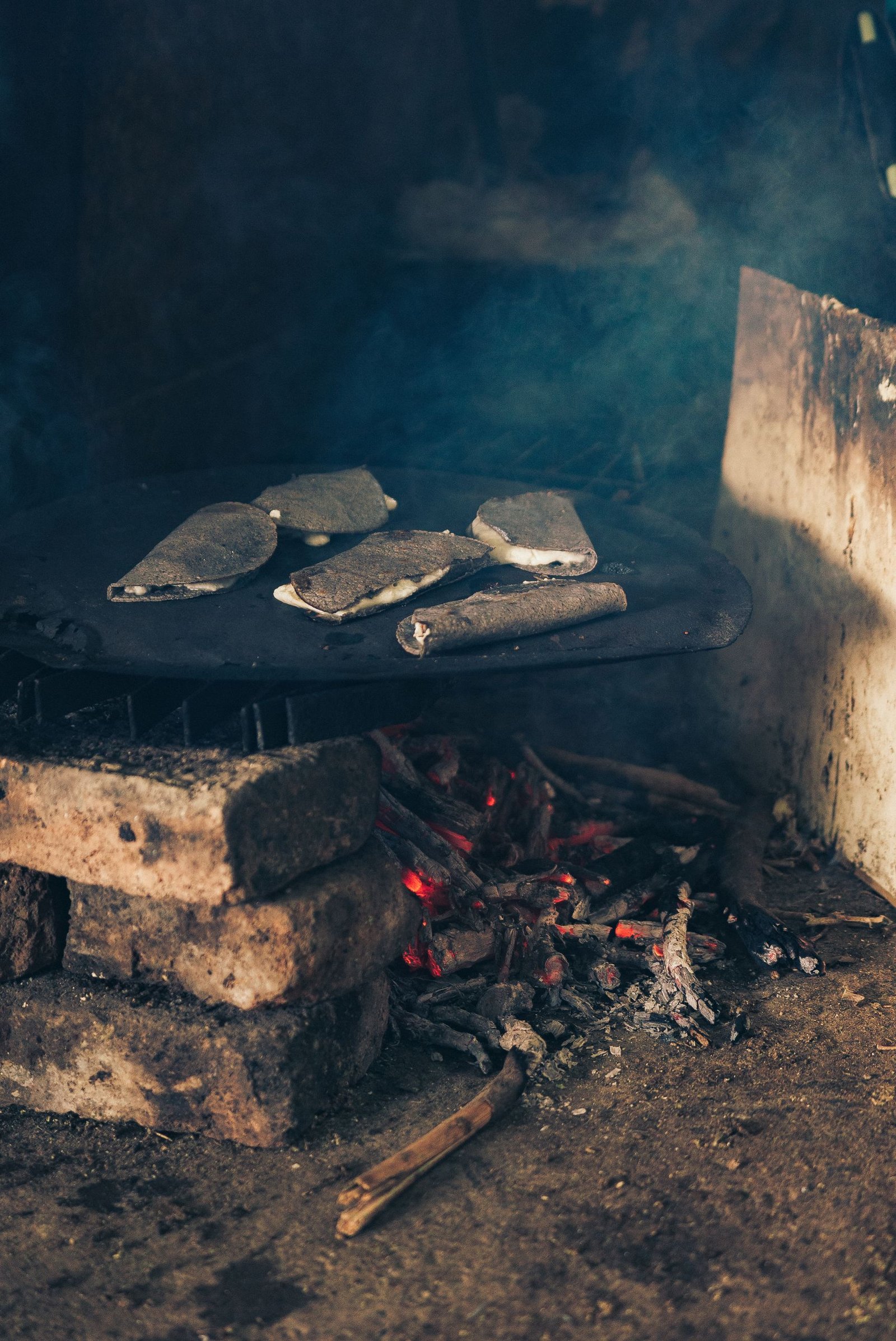 High angle of traditional Mexican flatbread with cheese grilling on hot smoldering steaming coals
