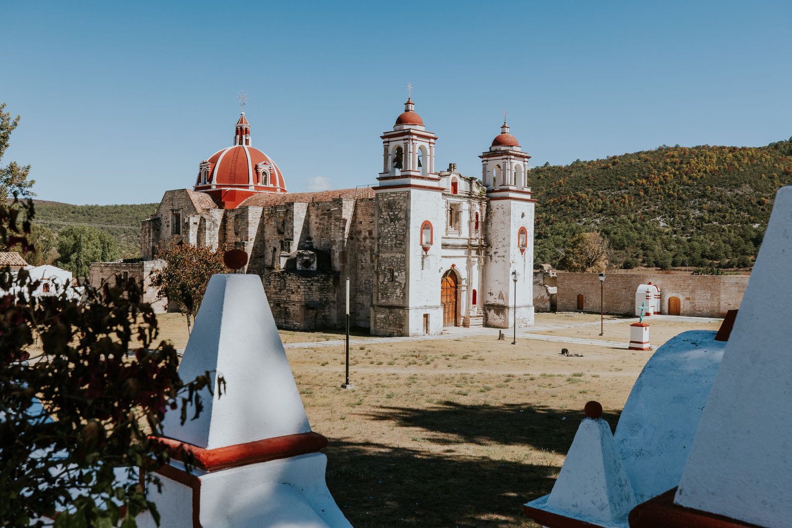 Historic church with red domes in a rural landscape under clear blue skies.