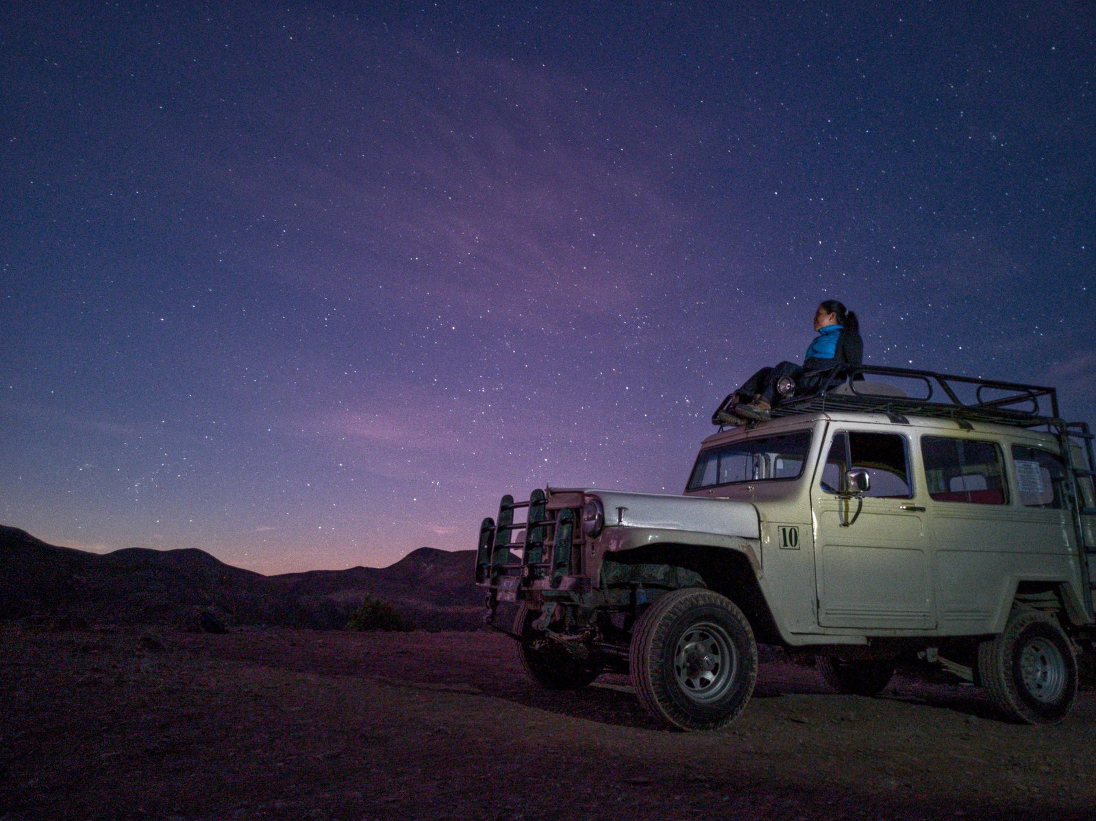 Person sitting on SUV under a starry sky in Real de Catorce, Mexico.