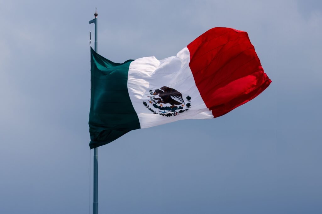 The Mexican flag proudly waves against a clear blue sky in Ciudad de México, showcasing its national symbol.