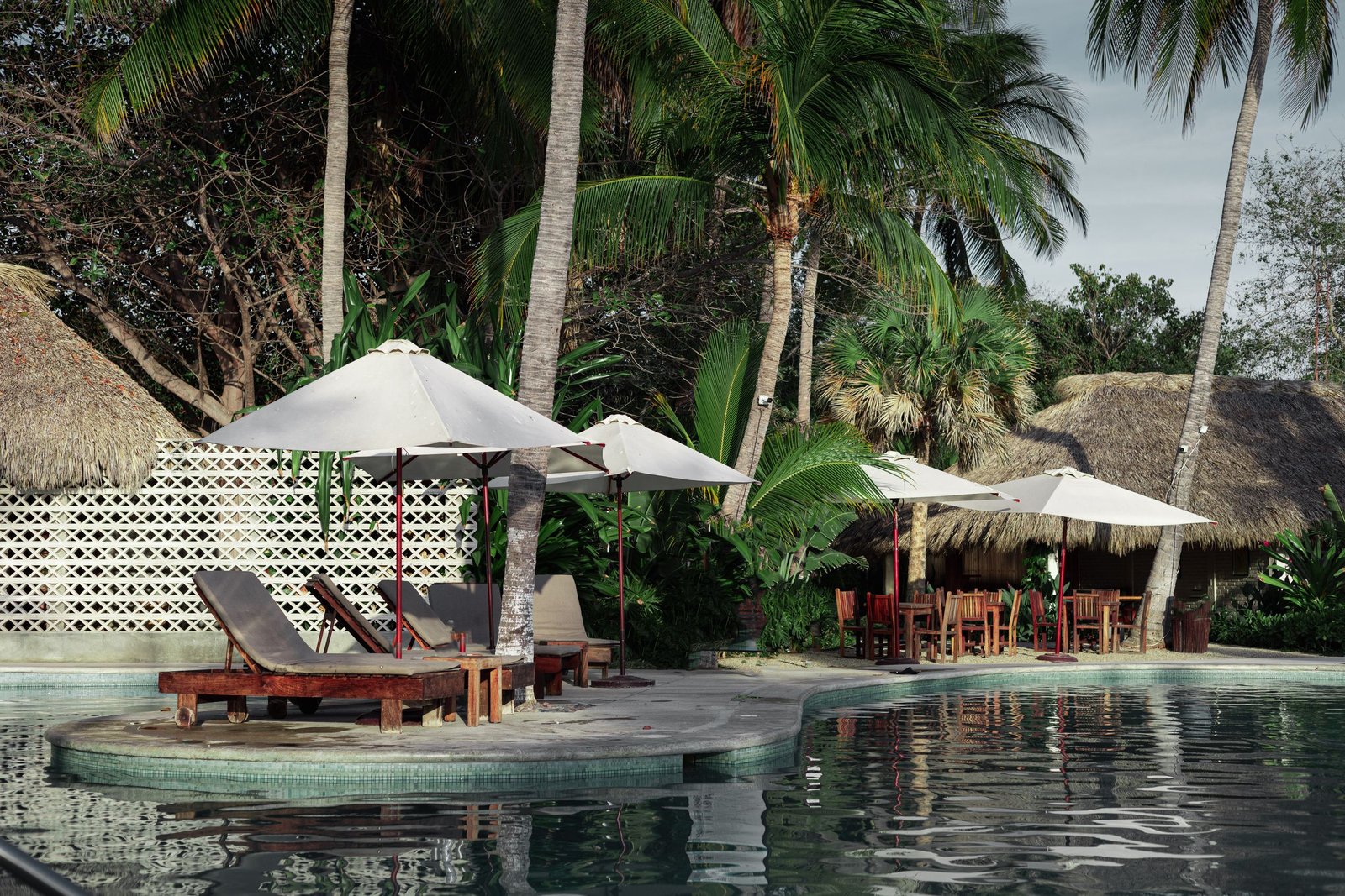 Relax by the tranquil poolside with palm trees and umbrellas in Puerto Escondido.
