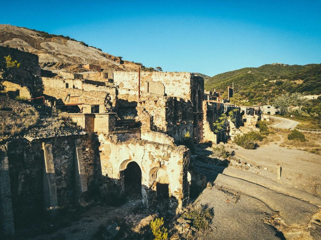 Ruins of ancient stone castle located on hill slope against cloudless blue sky on sunny day
