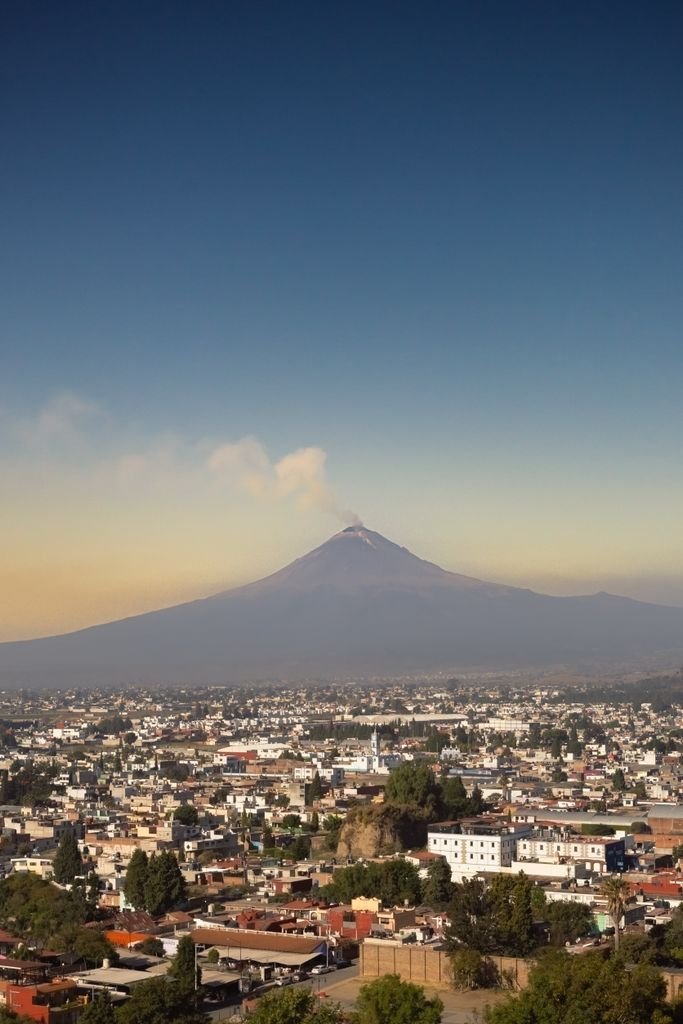 Scenic view of Cholula city with the Popocatépetl volcano in the background under a clear sky.