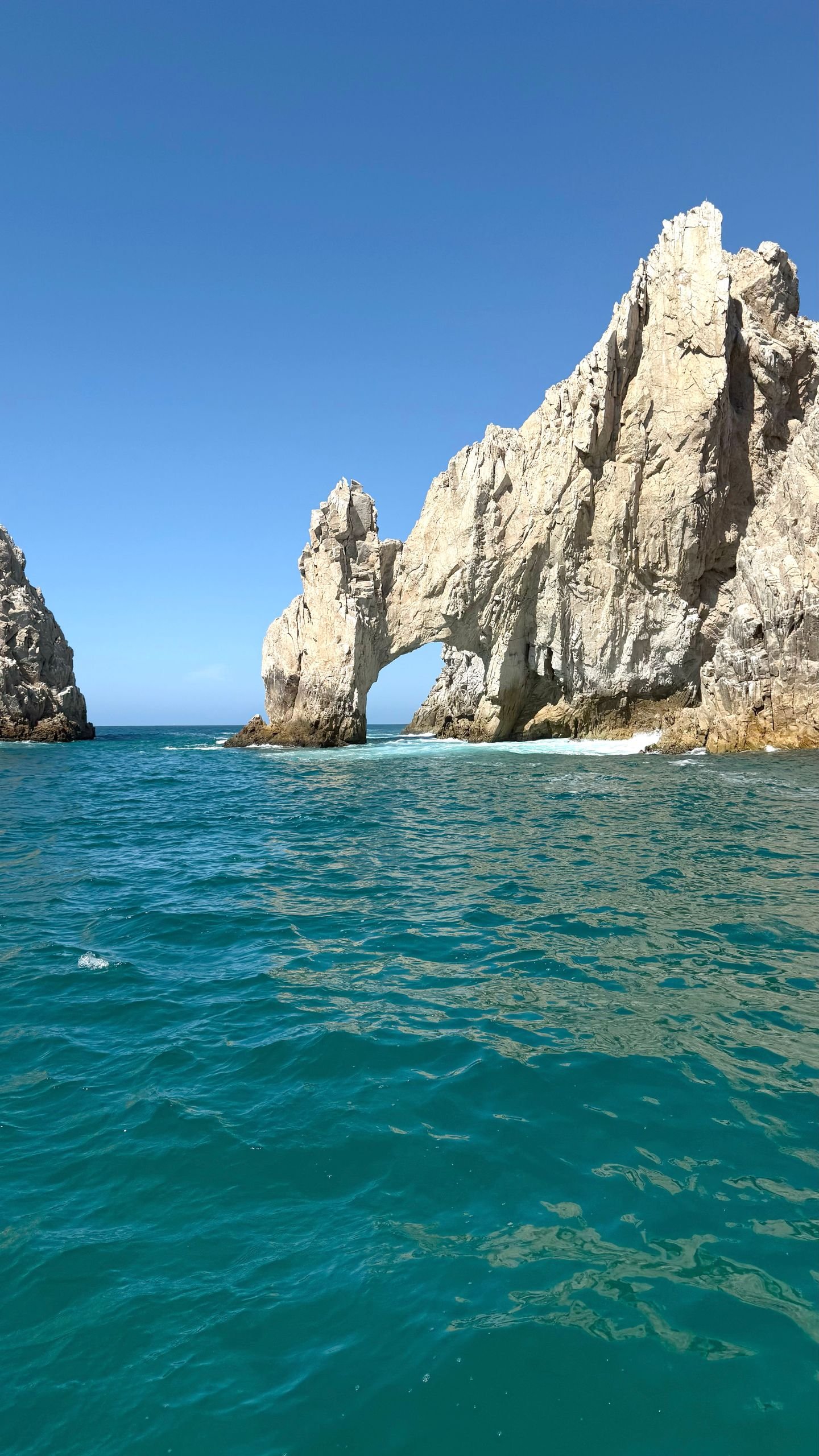 Stunning view of El Arco rock formation with turquoise waters under blue sky.
