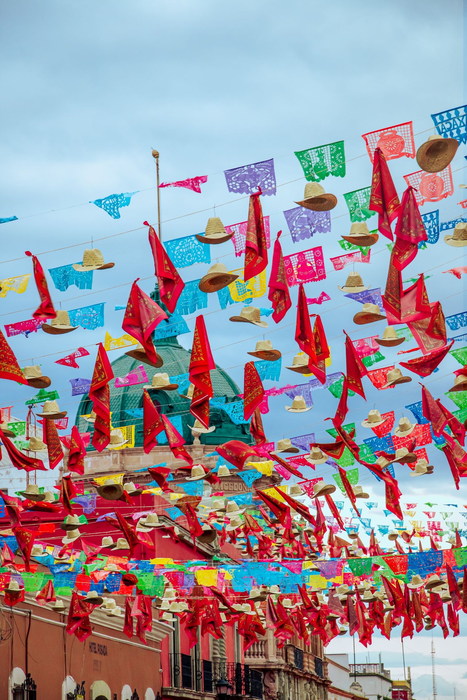 Vibrant paper flags and sombreros adorn Oaxaca street during Mexican celebration.