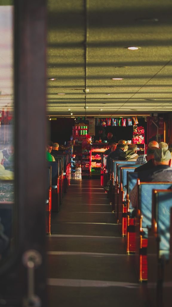 A bustling train lounge with people sitting and rows of seats, creating a warm atmosphere.