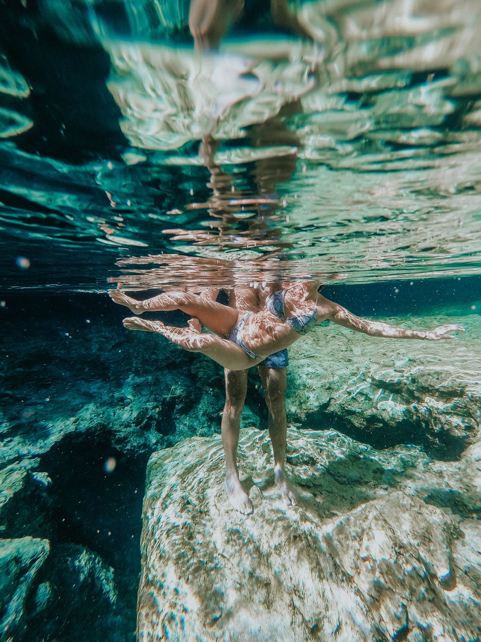 A couple explores the vibrant underwater world, showcasing the beauty of clear turquoise waters and rocky seabeds.