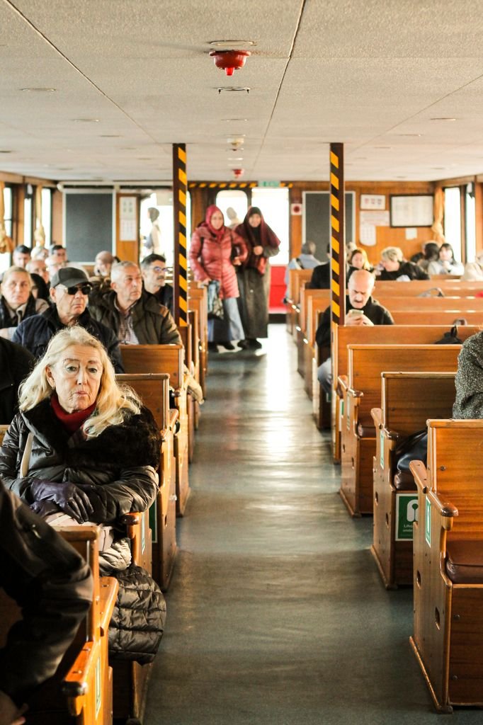A diverse group of passengers seated inside a ferry, capturing the essence of daily commuting and travel.