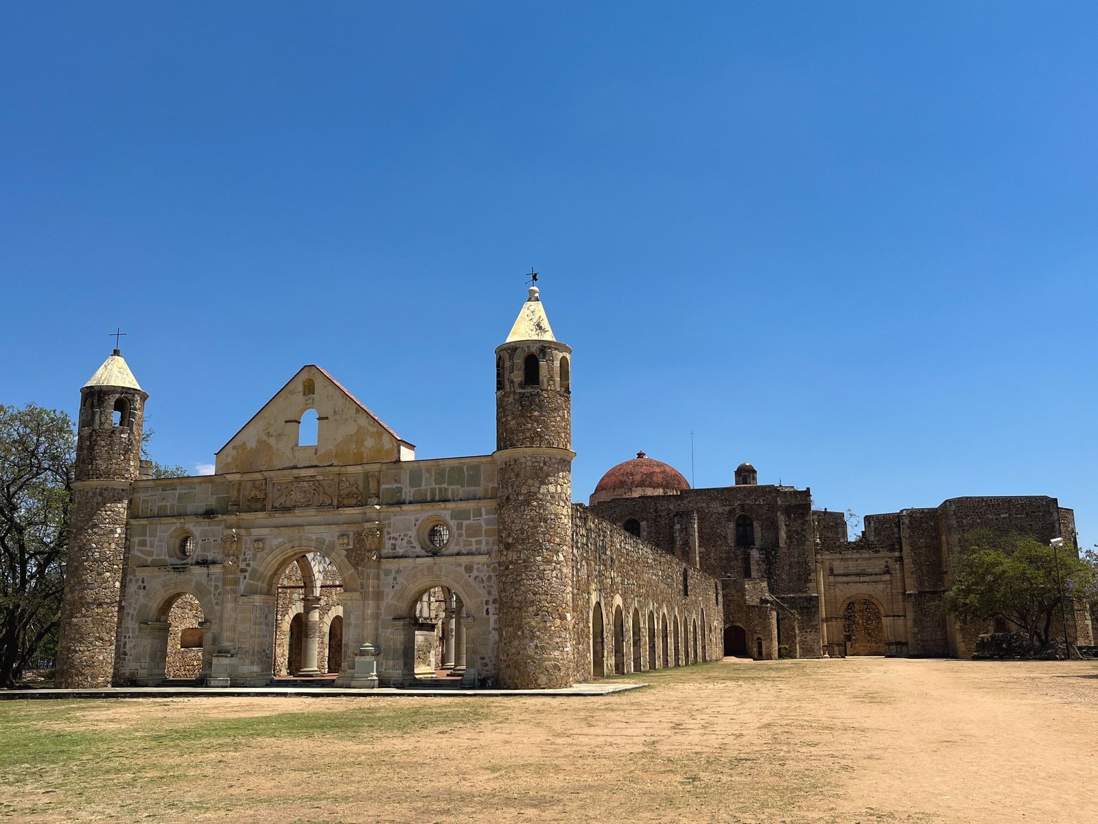 Ancient stone church in Oaxaca, Mexico, with clear blue skies, showcasing historic architecture.