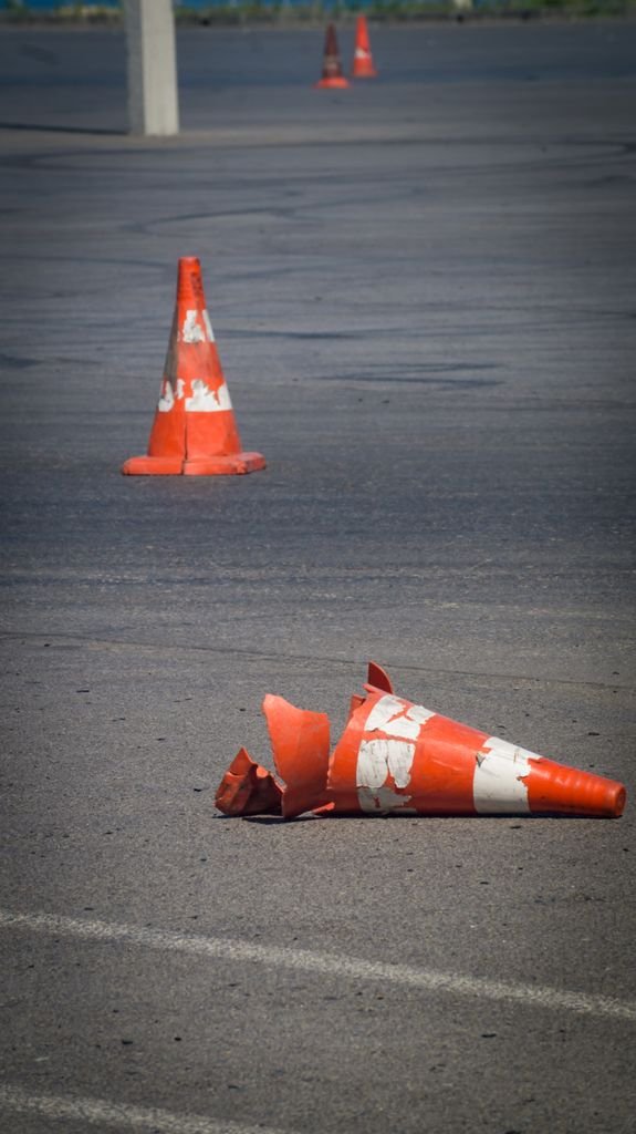 Close-up of two traffic cones on a city pavement, one broken, highlighting urban decay.