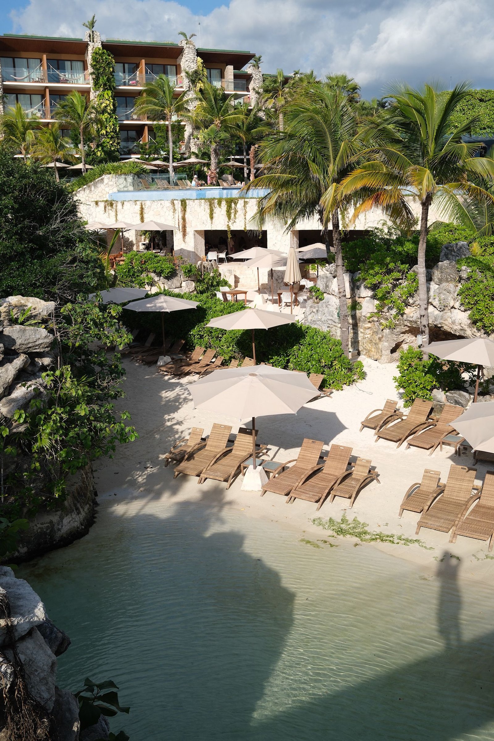 Discover a tranquil beachside resort in Tulum, featuring palm trees and sun loungers.