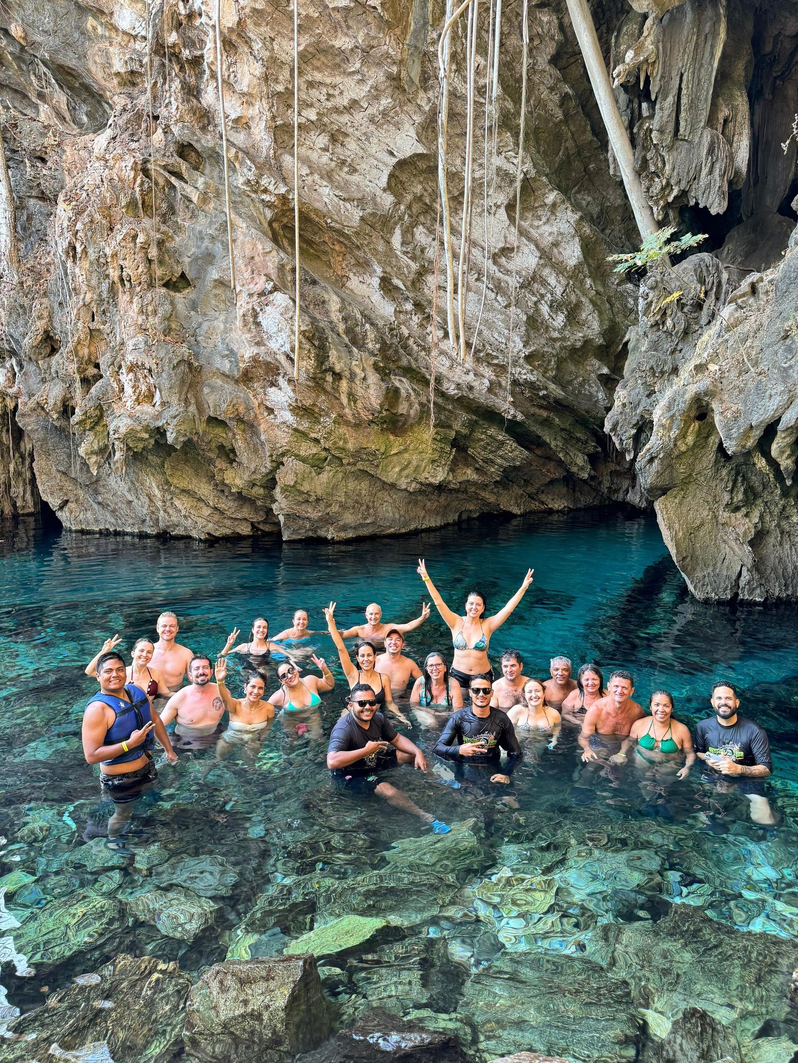 Group of adults swimming in crystal clear cave pool, enjoying nature.