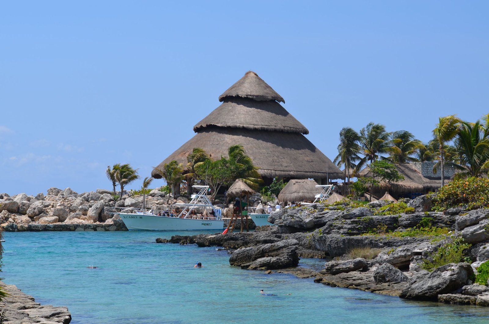Idyllic view of Xcaret Park beach with traditional hut and turquoise waters, perfect for a tropical getaway.