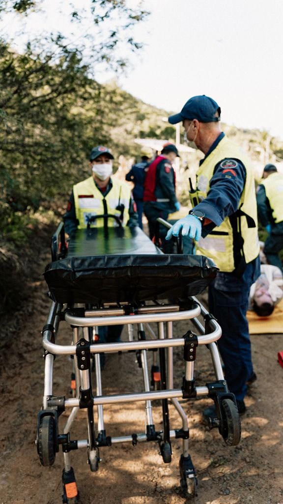 Rescue team performing emergency medical simulation outdoors with stretcher and equipment.