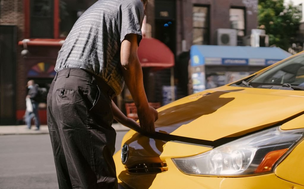 Side view of crop anonymous ethnic man opening cab hood parked on roadside