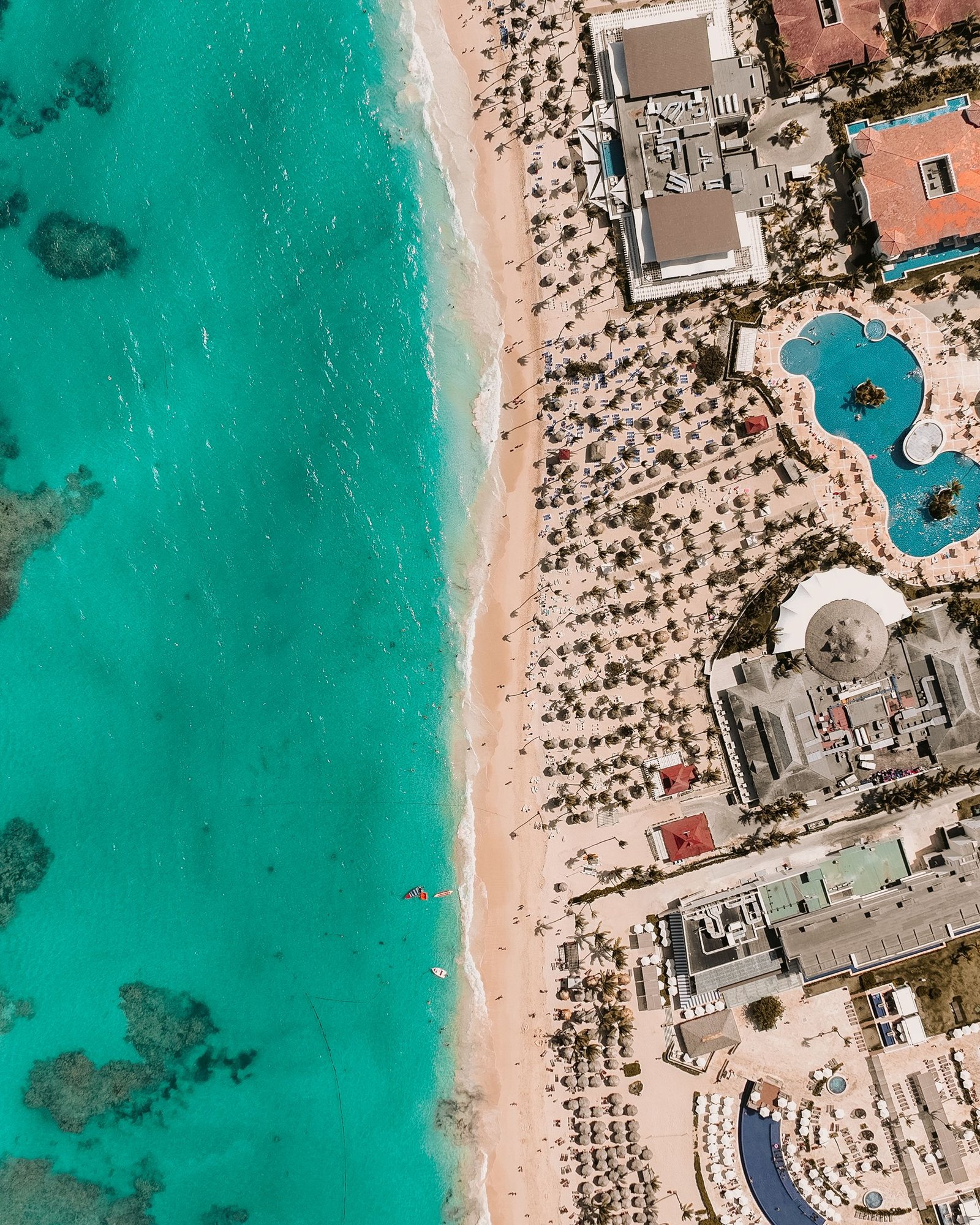 Stunning aerial view of a tropical beach with turquoise water and a luxury resort.