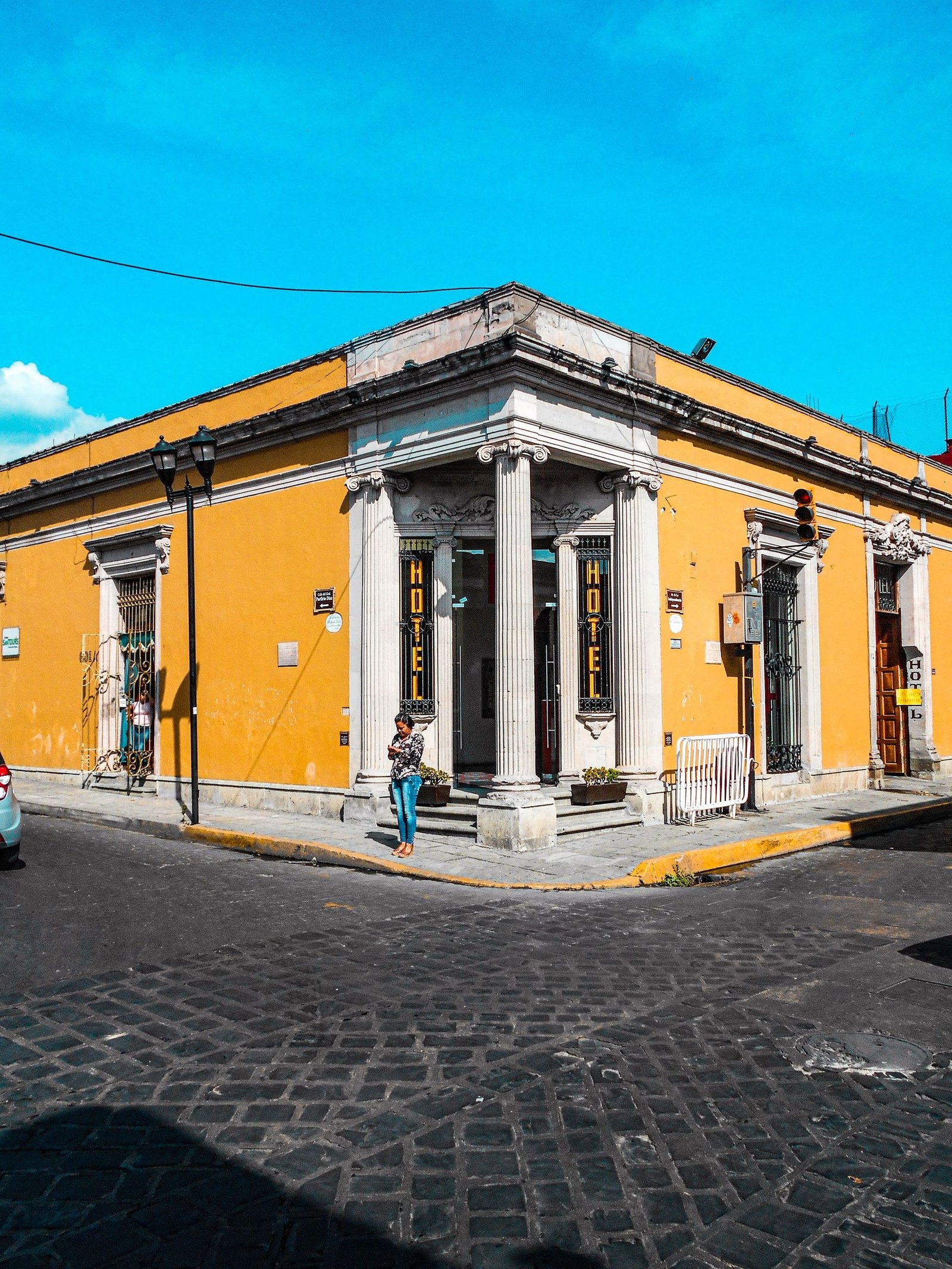 Vibrant yellow building on a sunny street corner in Oaxaca, perfect for urban exploration.