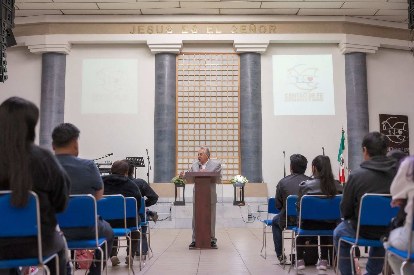 Speaker giving a lecture in a religious auditorium with attentive audience.