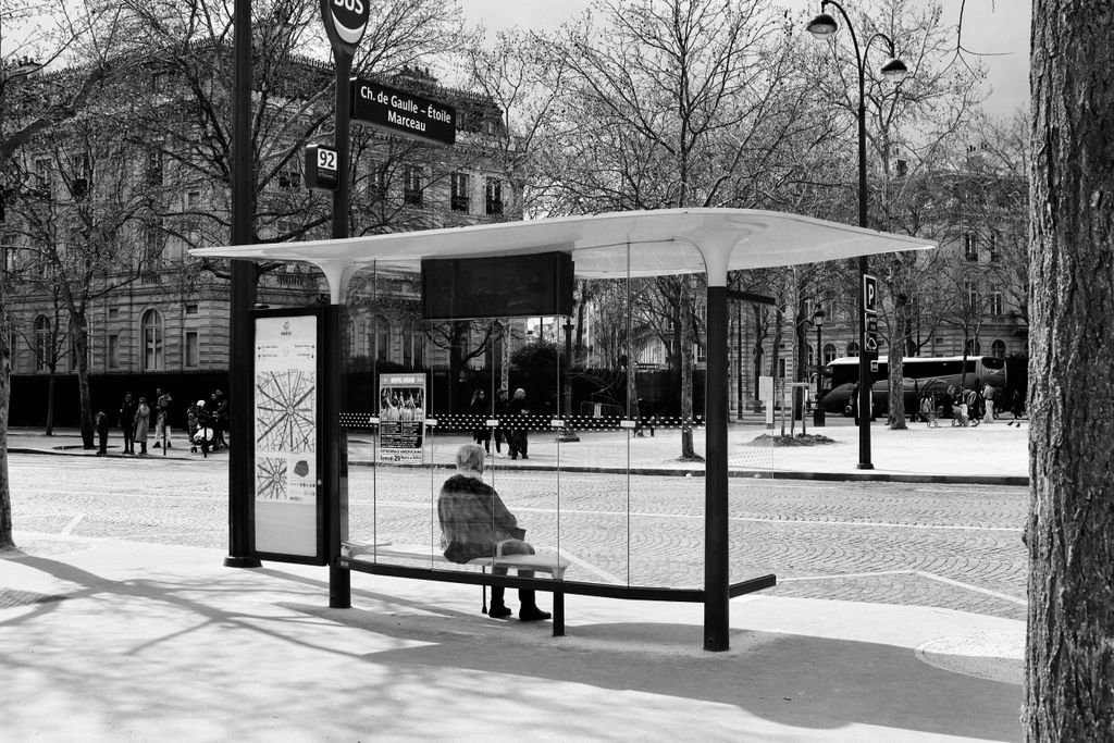 Monochrome image of a bus stop in Paris, showcasing urban life.